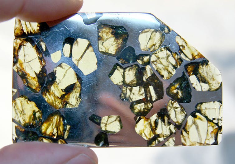 A rock made up of metal, with translucent olivine crystals suspended within.